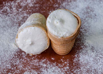 White cream ice cream in a waffle cup. Ice cream in icing sugar. Simple cold dessert