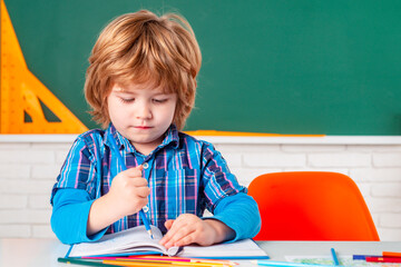 Schoolkid or preschooler learn. Cute child boy in classroom near blackboard desk. Kids from primary school. Happy school kids at lesson.