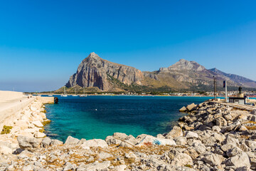 A view across the harbour entrance at San Vito lo Capo, Sicily with impressive mountain backdrop in summer