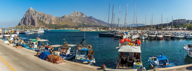 A panorama view across the harbour of San Vito lo Capo, Sicily with impressive mountain backdrop in summer - obrazy, fototapety, plakaty