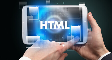 Close-up of a hand holding tablet with HTML abbreviation, modern technology concept