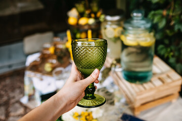 Woman holding a green glass of lemonade at an open air party.