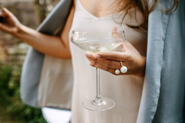 Woman dressed in white dress holding a coupe with champagne at a party. - obrazy, fototapety, plakaty