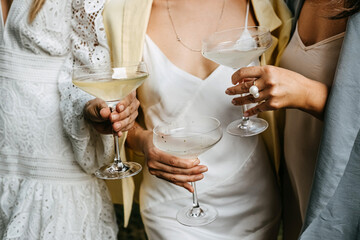 Women wearing summer dresses, holding coupes with champagne at a party.