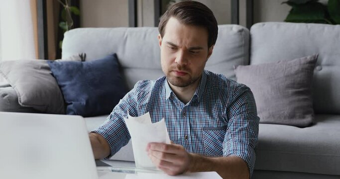 Man sitting in living room do finance analysis holds sales slip heap of receipt feels frustrated worried due lack of money, small business entrepreneur bankruptcy financial problems, overspend concept