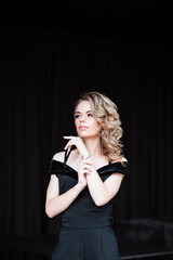 Beautiful blonde, young girl. Portrait of a young girl in a restaurant. Young girl in a restaurant on a black background. Portrait of a girl in a black dress. Young girl.