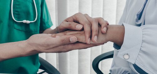 Doctor shook hands to comfort the male patient in the hospital room.