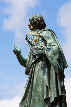 Nicolaus Copernicus Monument, statue of polish renaissance astronomer, Torun, Poland. Sculpture with a protective mask, Covid-19 pandemic time