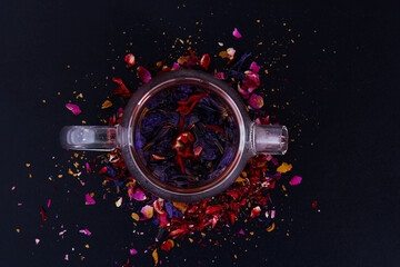 Different types of coffee and enough types and drinks in the black background in the top view, which is poured on a wooden board with pieces of flowers.