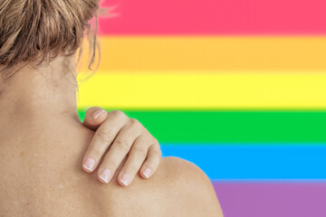 back of a woman with a female hand on her shoulder and a rainbow flag in the background. LGBT pride...