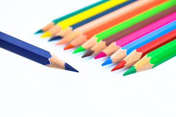 Line of different colored wood pencil crayons pointing at a purple color pencil