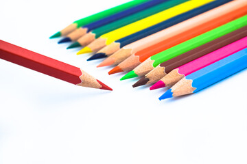 Line of different colored wood pencil crayons pointing at a red color pencil