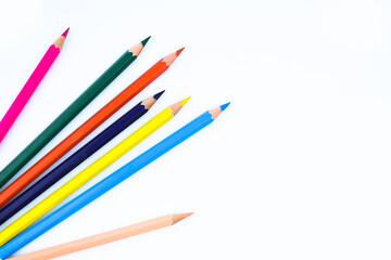 Six different colored wood pencil crayons scattered on a white background