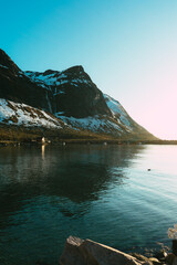 Polar day in northern Norway - sunset, azure sea, sun reflections, mountain and seagull on the beautiful water.
