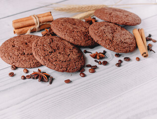 composition of oat cocoa cookies decorated with coffee beans, star anise, cinnamon sticks, cloves, wheat on a white wooden table background .place for text. copy space. image design for menu layout