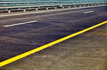 Modern asphalt highway with bright road marking. Asphalt road surface close-up. Highway car drive in countryside. Traveling by car. Transportation road system. Modern countryside roads infrastructure