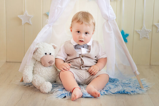 child 1 year a boy in a suit sits with a bear in a wigwam in a photo Studio, Birthday of a child 1 year