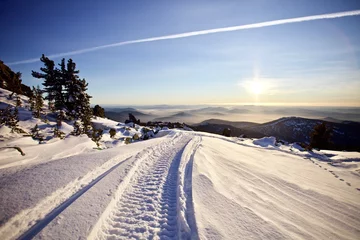 Fotobehang Winter road through the snowy valleys in the mountains. Snowy mountains winter landscape on bright clear blue sky background. Sunny snowy day in Siberian mountains. Snowy road among the mountains. © ST-art