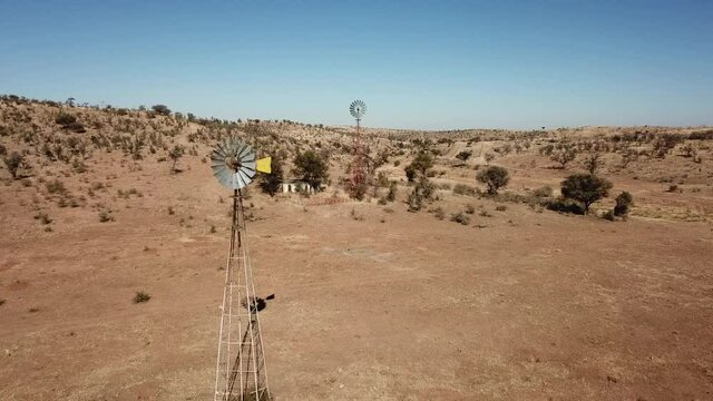 4K aerial drone video of Africa savanna hills, plains and farm wind water pumps on pillars in dry riverbed near Neuheusis west of Windhoek in central highland of Namibia, southern Africa