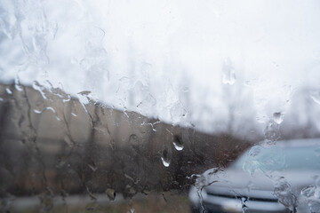 view from the car window with dripping raindrops and a blurry view