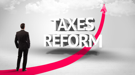 Fototapeta premium Rear view of a businessman standing in front of TAXES REFORM inscription, successful business concept