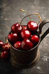 Freshly harvested cherries in vintage metal cup. Selective focus. Shallow depth of field.