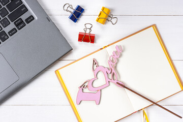 Laptop, paper clips, love sign and notepad on white wooden background