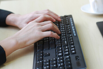 Close up on asian businessmen hands typing Keyboard with a cup of coffee on computer desk in office