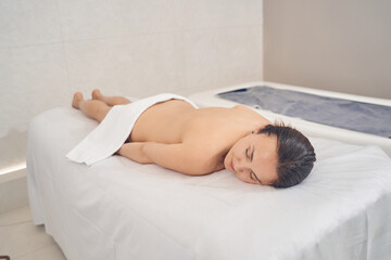 Beautiful lady lying without clothes on medical couch