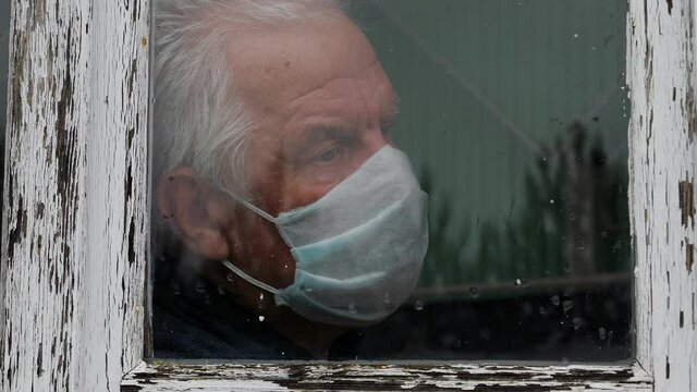 At Pandemic Covid Old Man In Medical Mask Looks Sadness Out Of Window At Street