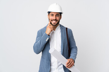 Young architect man with helmet and holding blueprints isolated on white background smiling with a happy and pleasant expression