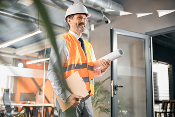 Senior architect arriving at the office with blueprint