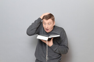 Funny shocked man is reading something extraordinary in book