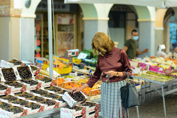 60s 70s senior attractive elegant caucasian european lady walking in the small city open market...