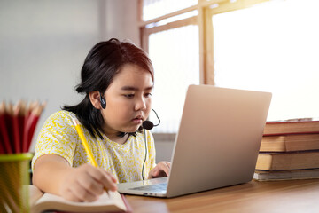 An Asian girl is studying online. education concept with laptops homework math during her online lesson at home, social distance during quarantine, self-isolation