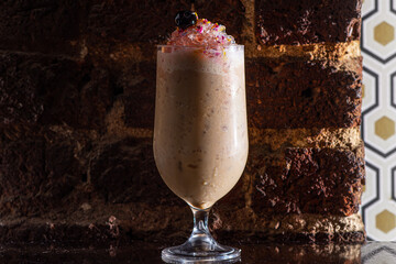 milky cocktail in hurricane glass on brick background