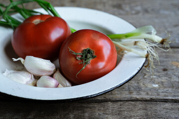 Fresh tomatoes, garlic, and scallions on old wooden table.