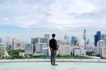 Fototapeta na wymiar Businessman standing on building. City background with copy space. Success and vision concept