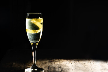 French 75 champagne cocktail with lemon zest on black background