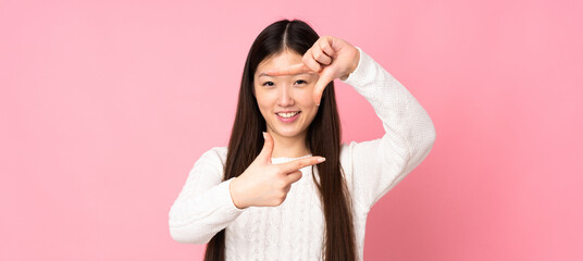 Fototapeta premium Young asian woman over isolated background focusing face. Framing symbol