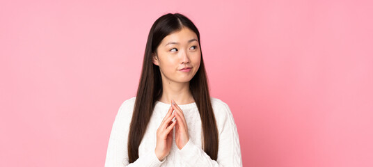 Young asian woman over isolated background scheming something