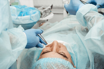 Dentists will perform an operation, implant placement. Real operation. Tooth extraction, implants. Professional uniform and equipment of a dentist. Healthcare Equipping a doctor’s workplace. Dentistry