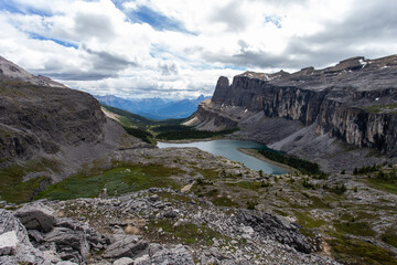 high view of a lake surrounded by a rock wall in the mountains on a cloudy day