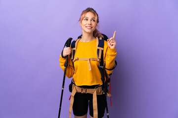 Teenager girl with backpack and trekking poles over isolated purple background pointing up a great idea