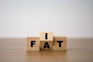 Fit and fat wording print screen on wooden cube block. Diet and good health condition.