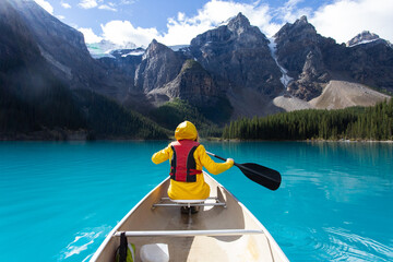 Girl kayaking on a turquoise lake with a yellow rain jacket 