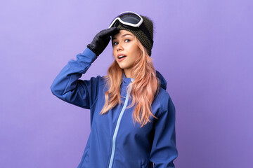 Skier teenager girl with snowboarding glasses over isolated purple background doing surprise gesture while looking front