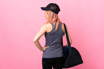 Teenager sport woman with sport bag over isolated background in back position and looking side