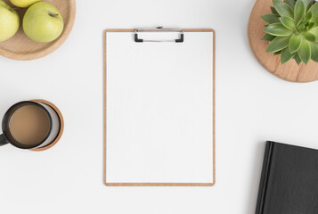Top view of a wooden clipboard mockup with a succulent plant, apples and a coffee on a white table.