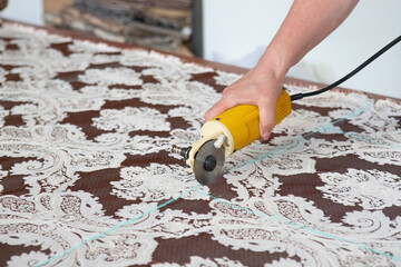 Seamstress tailor with electric cutting cuts the fabric in the studio.